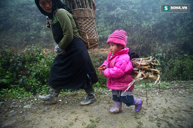 Bé gái Mông mặc 1 chiếc áo khoác ấm do đoàn từ thiện trao tặng đang đi lấy củi cùng mẹ. Ảnh: Na Sơn.