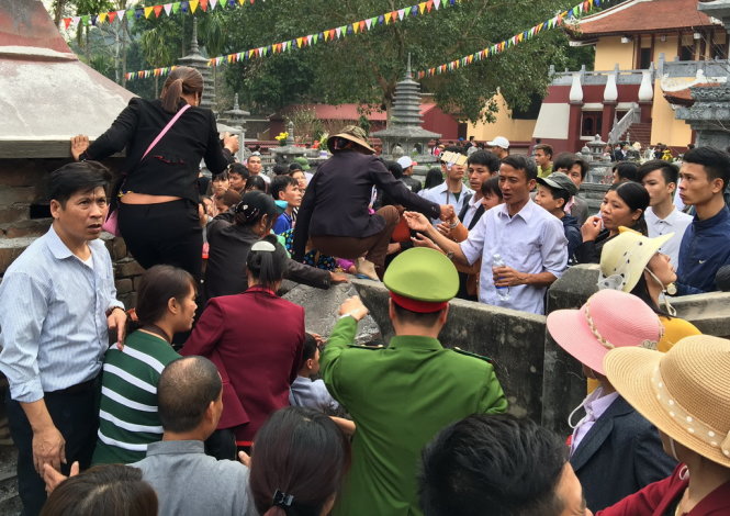 Nhiều du khách bất chấp việc ngăn cản của lực lượng chức năng vẫn trèo tường giành đường vào chùa trước khi cử hành lễ khai hội - Ảnh: Xuân Long