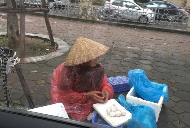 Cụ bà đội mưa bán trứng bên vỉa hè khiến nhiều người xúc động.