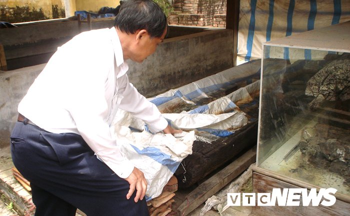 Ông Tăng Bá Hoành bên những chiếc mộ thân cây được bảo quản sơ sài ở Bảo tàng Hải Dương.