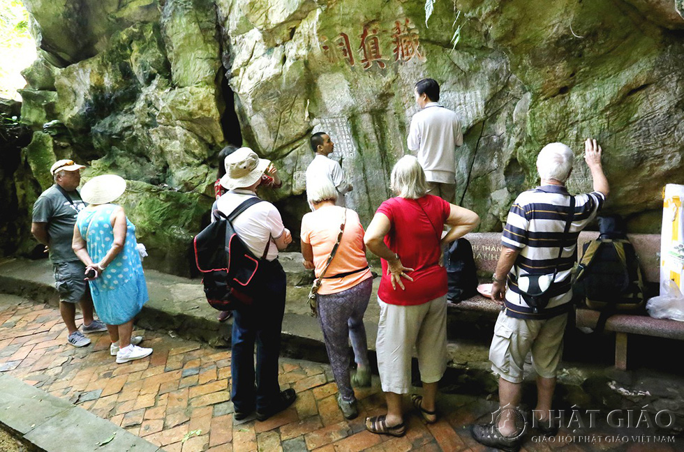 Du khách thích thú xem các nhà nghiên cứu xử lý các bản ma nhai trên vách đá Ngũ Hành Sơn - Ảnh: NGUYỄN VĂN THỊNH