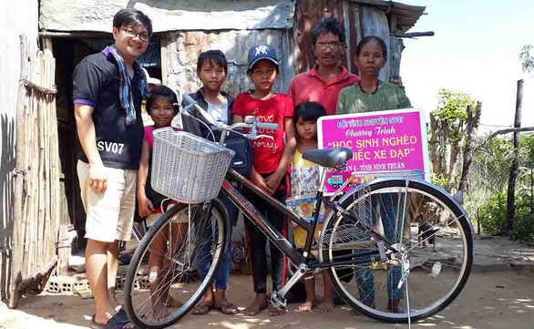 Anh Châu Thành Toàn (bìa trái) trao chiếc xe đạp cho một học sinh nghèo ở miền Tây - Ảnh: PHƯƠNG HOA