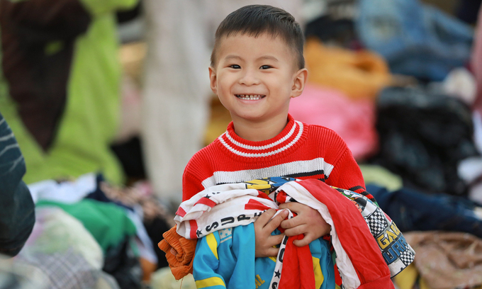 Niềm vui của Gia Khánh, 3 tuổi, ở xã Cam Thủy, huyện Lệ Thủy, Quảng Bình khi được tặng rất nhiều áo ấm sau nhiều ngày co ro vì mưa bão. Ảnh: Hữu Khoa.