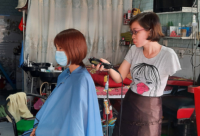 Với kiểu tóc cắt ngắn hoặc tóc tém người thợ phải dùng lược để cố định lớp tóc thường xuyên để cắt nên với chị Trâm đây là hai kiểu tóc khó. Tuy nhiên, chưa đầy 10 phút, chị đã cắt xong với sự kết hợp của tông đơ và kéo. Ảnh: Diệp Phan.