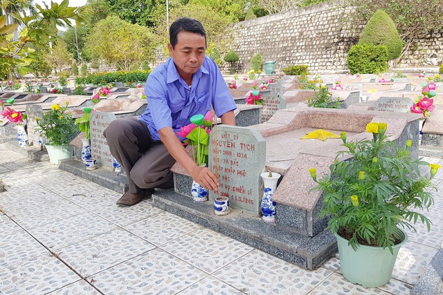 Người quản trang Bùi Ngọc Trừ bên phần mộ liệt sĩ tại nghĩa trang liệt sĩ Hòn Dung (TP Nha Trang)