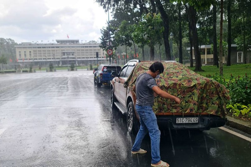 Anh Nguyễn Chí Đức đội mưa căng bạt che chắn, bảo vệ số hàng hóa trên xe để kịp đưa đến các điểm tập kết phục vụ bà con. Ảnh: CRV