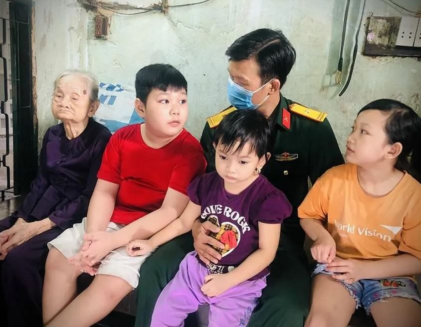 Thiếu tá Nguyễn Trung Kiên cùng ba người con mà anh nhận đỡ đầu trong một lần bàn giao tro cốt nạn nhân tử vong do COVID-19 về với gia đình. Ảnh: NVCC