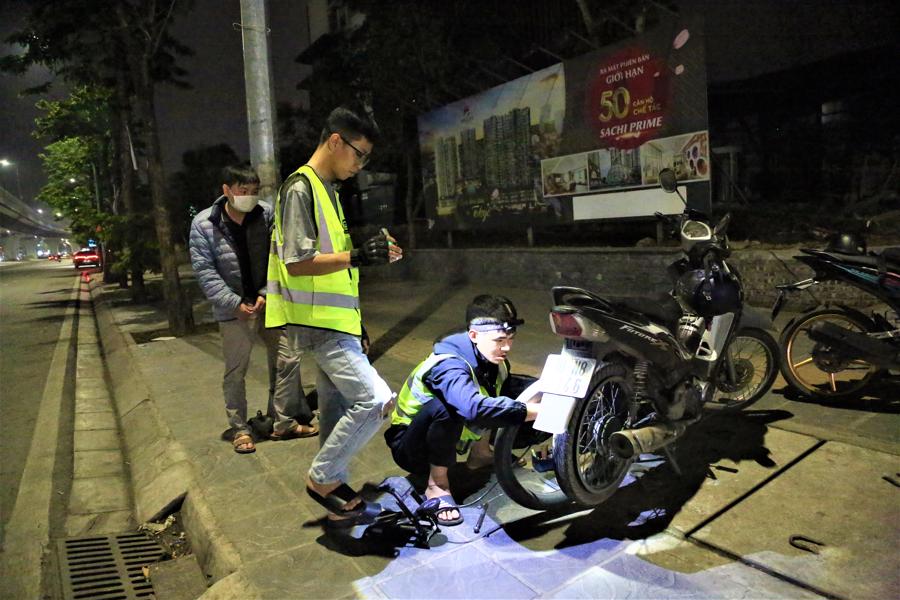 Các thành viên đội Cứu hộ Hà Nội sửa xe miễn phí trong đêm cho người đi đường. Ảnh: Phạm Công.