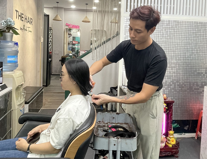 Anh Tuấn Anh cắt tóc cho một người hiến tóc vì bệnh nhân ung thư tại cửa hàng ở quận 3, TP HCM, ngày 28/6/2023