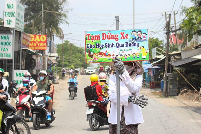 Bà Phượng đứng cầm bảng xin đường cho học sinh di chuyển sang đường trưa ngày 8/4. Ảnh: Diệp Phan.