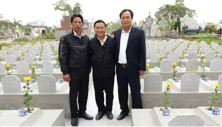 Ông Phạm Xuân Cử (ngoài cùng bên phải) chụp ảnh tại khu nghĩa trang quy tập các phần mộ vô danh do ông đầu tư xây dựng